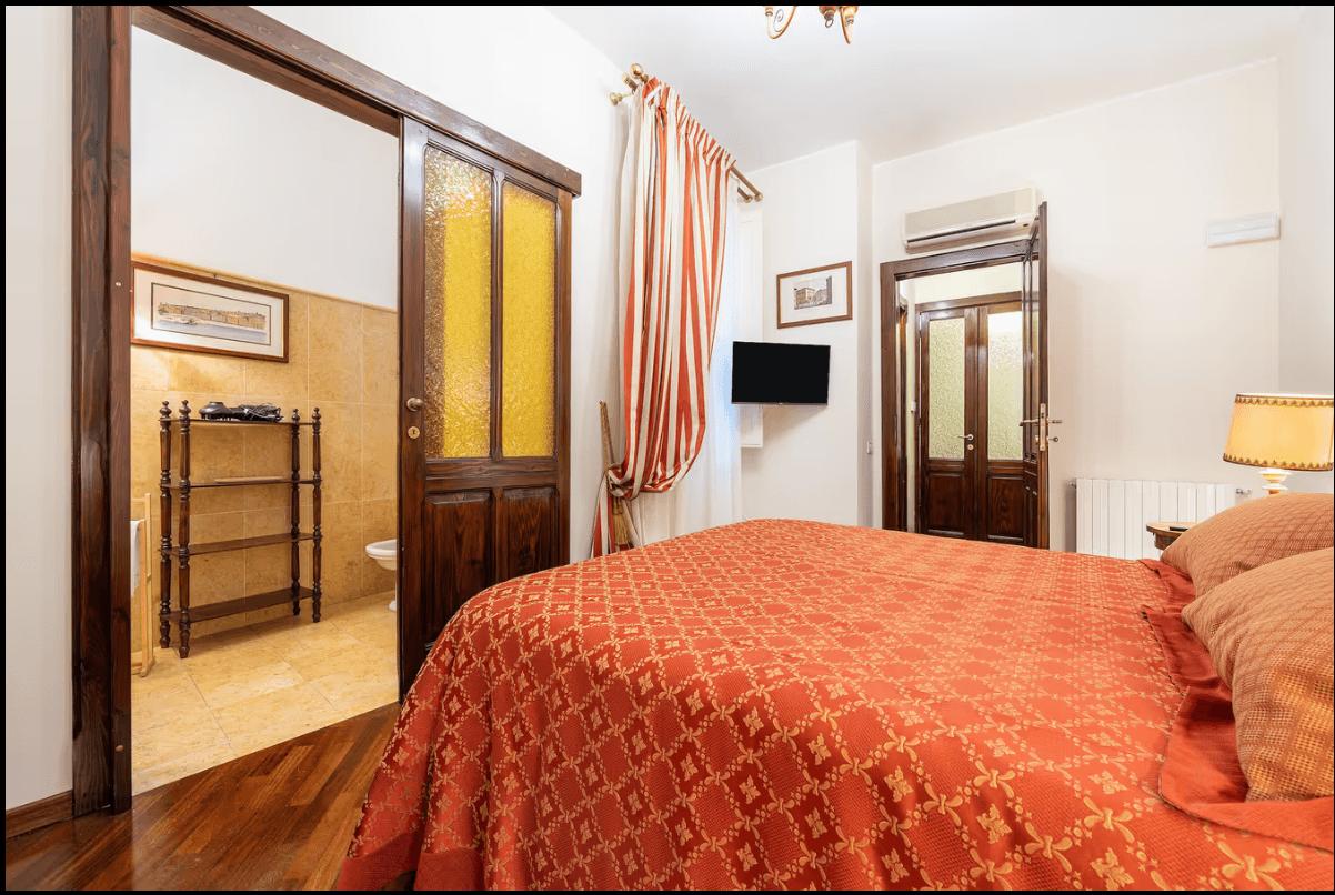 Master bedroom with red bedspread at ĀMĪTA